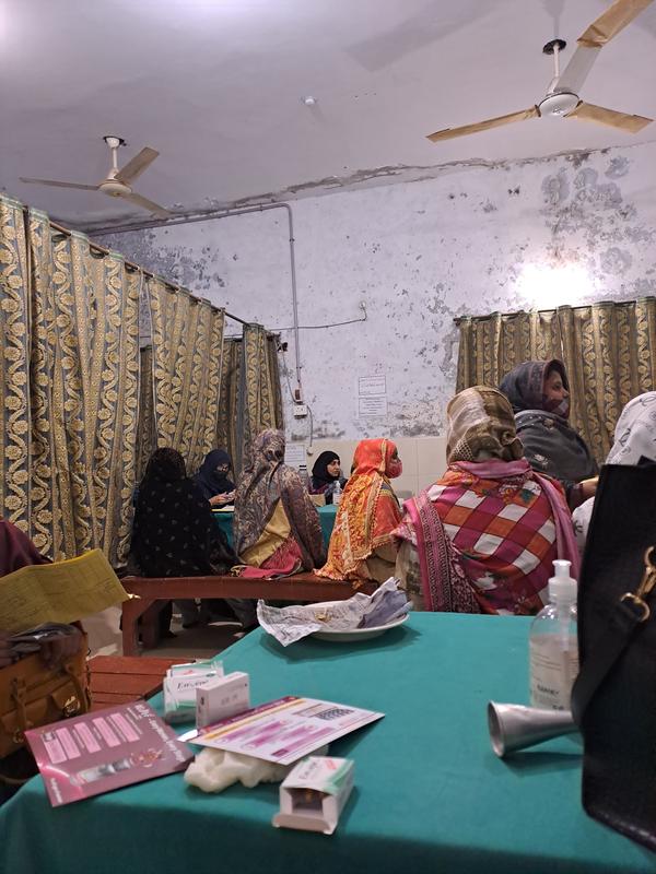 Women seated in a clinic room while staff record details at a table